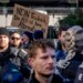 Police officers stand next to demonstrators with a sign "no Friedrich, the AfD is no alternative" during a protest against an AfD election campaign in Neu Isenburg near Frankfurt, Germany, Saturday, Feb. 1, 2025. (AP Photo/Michael Probst)